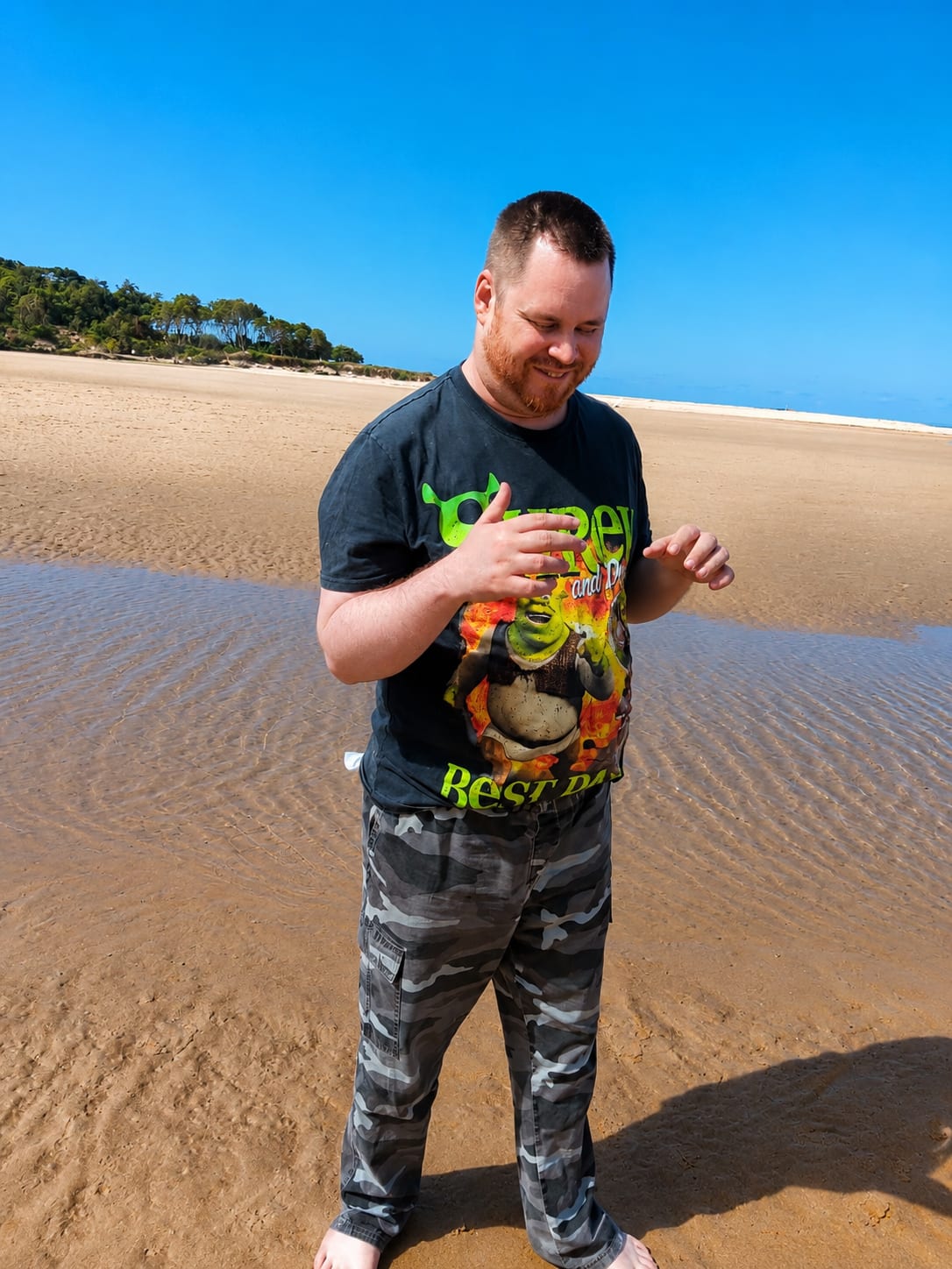 Standing at the water’s edge on a wide sandy beach on a clear day.