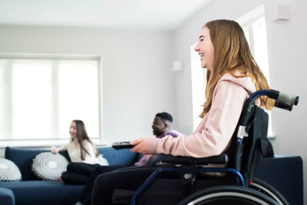 A disabled woman sitting in her wheelchair with her group of friends in the living room
