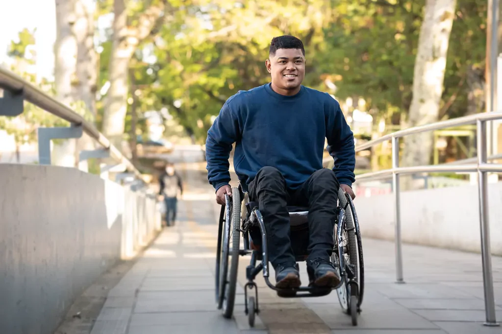 A disabled man smiling while sitting in his wheelchair outside
